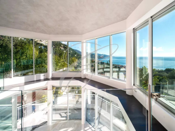 Interior of a modern villa with large windows offering a view of the sea.