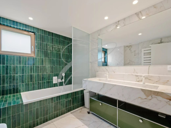 Modern bathroom with bathtub, green tiles and marble furniture.