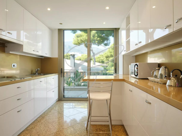Cuisine moderne avec meubles blancs et plan de travail en bois, vue sur l'extérieur.