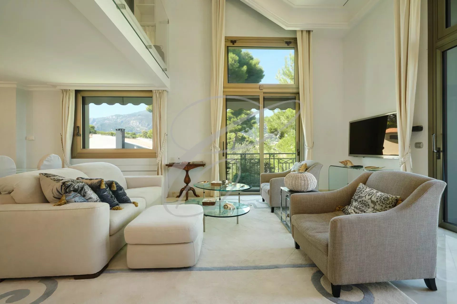 Intérieur d'un appartement de luxe à Roquebrune-Cap-Martin, salon lumineux avec canapé et vue sur la nature.