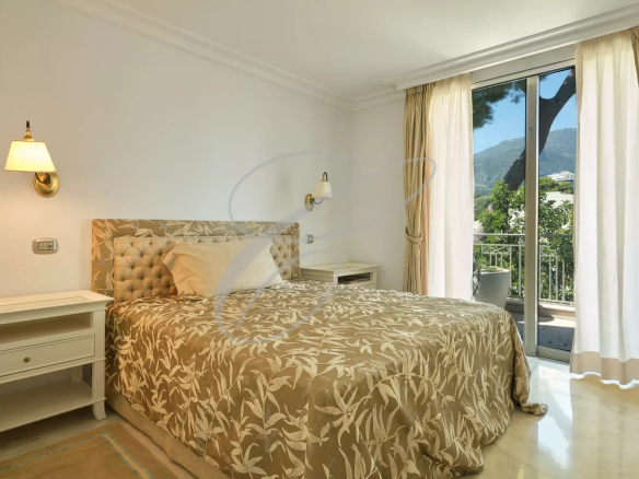 Chambre d'un appartement de luxe à Roquebrune-Cap-Martin avec lit et balcon.