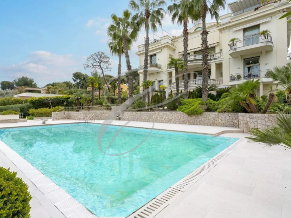 Piscine d'une résidence de luxe à Roquebrune-Cap-Martin, entourée de palmiers et de verdure.