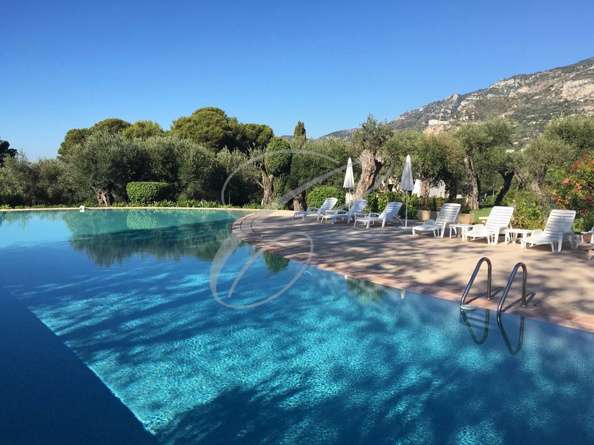 Piscine à Roquebrune-Cap-Martin Piscine d'une résidence avec chaises longues et vue sur la nature environnante à Roquebrune-Cap-Martin.