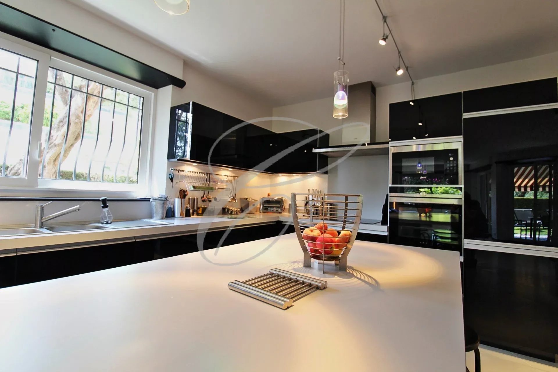 Cuisine d’un appartement à Roquebrune-Cap-Martin Cuisine moderne avec îlot central et vue sur le jardin, dans un appartement à Roquebrune-Cap-Martin.