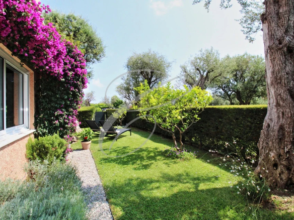 Jardin d'une résidence avec pelouse, plantes et mobilier de jardin à Roquebrune-Cap-Martin.