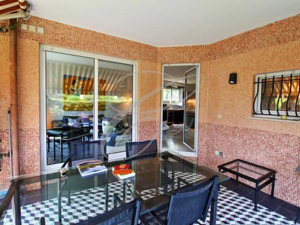 Terrasse d'un appartement avec mobilier de jardin, vue sur un espace vert.