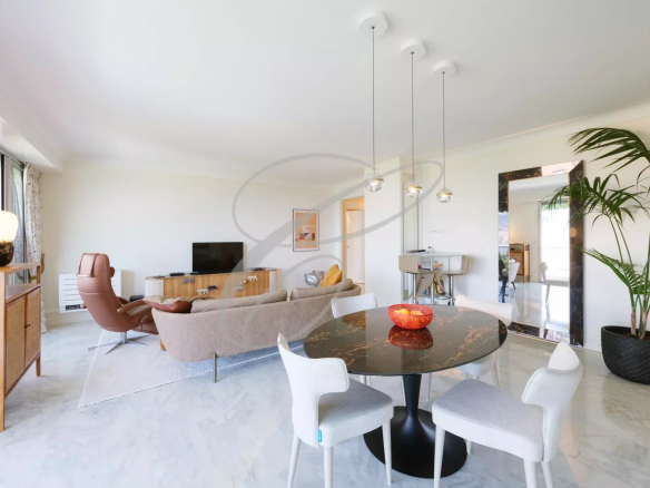 Intérieur d'un appartement moderne avec salon, salle à manger et vue sur la mer.