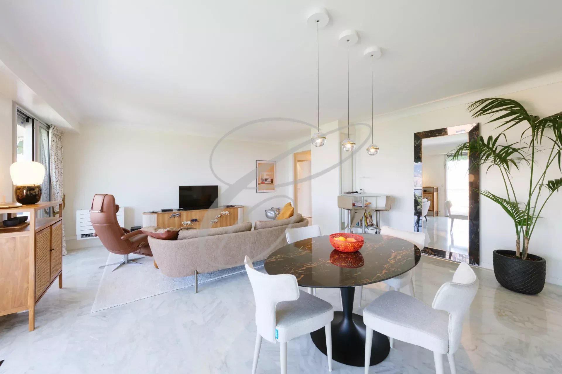 Intérieur d'un appartement moderne avec salon, salle à manger et vue sur la mer.