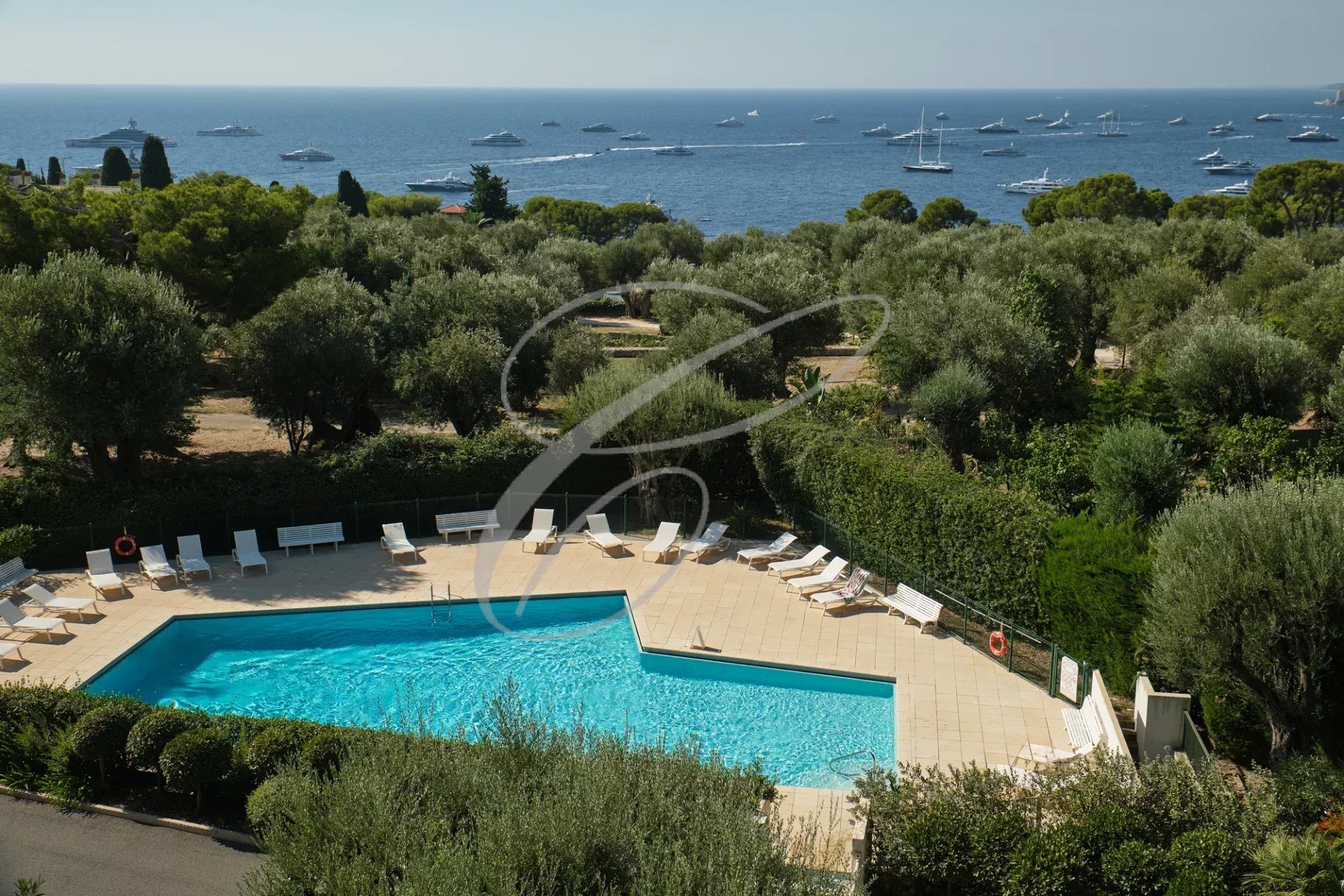 Vue de la piscine d'une résidence avec vue sur la mer et des bateaux au large à Roquebrune-Cap-Martin.