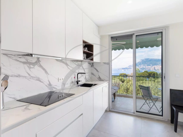 Cuisine moderne avec vue sur la mer et Monaco, fenêtres ouvertes sur la terrasse.