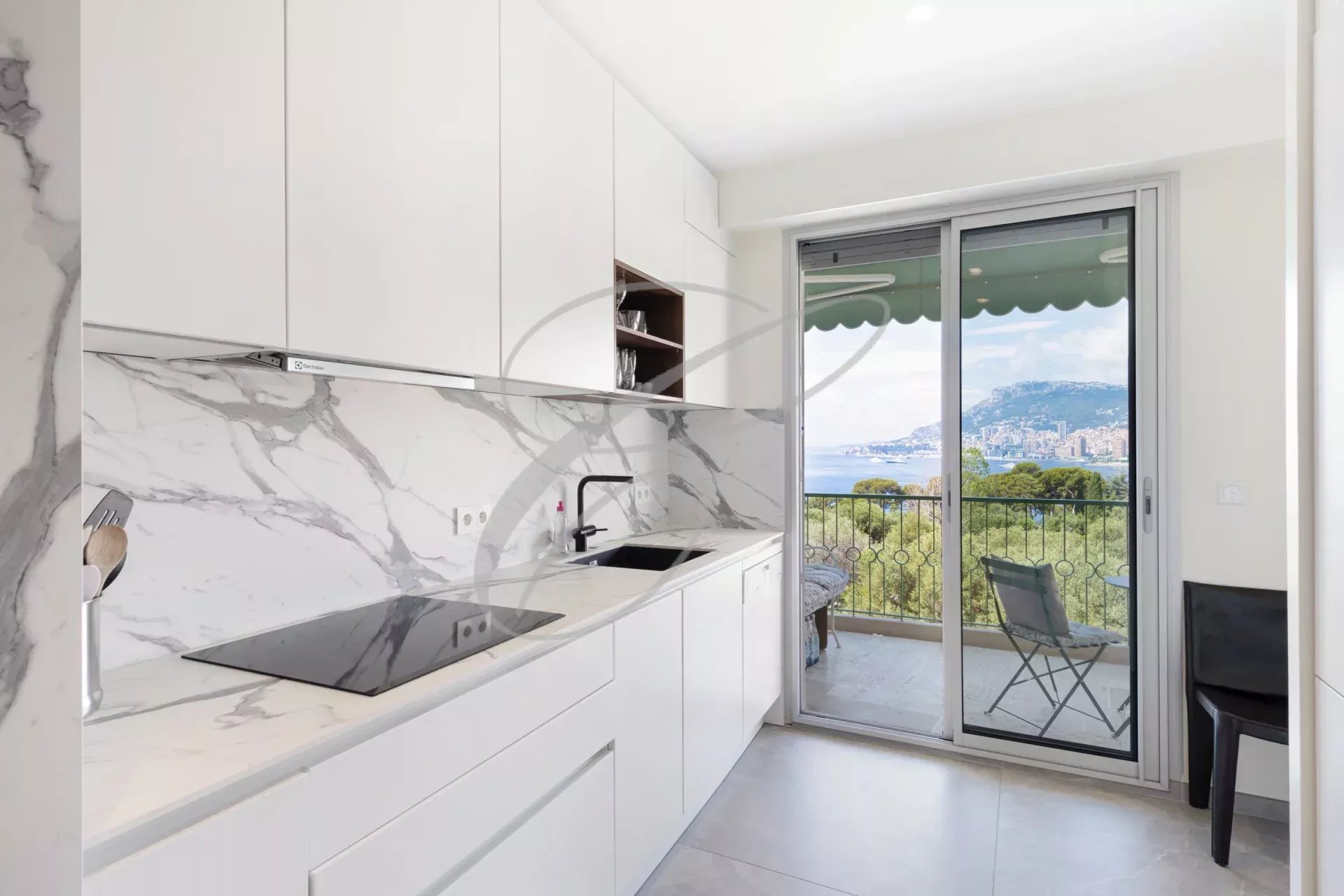 Cuisine moderne avec vue sur la mer et Monaco, fenêtres ouvertes sur la terrasse.