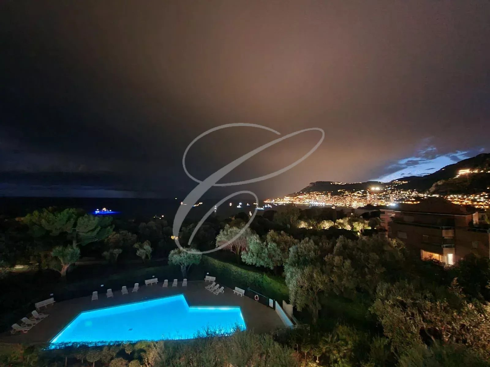 Vue nocturne sur la mer et Monaco depuis une résidence avec piscine
