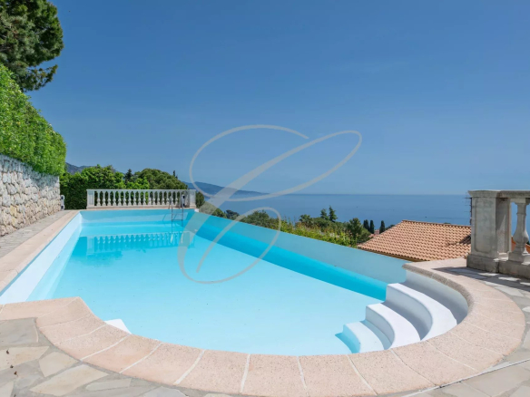 Swimming pool with sea view in Roquebrune-Cap-Martin, surrounded by greenery.