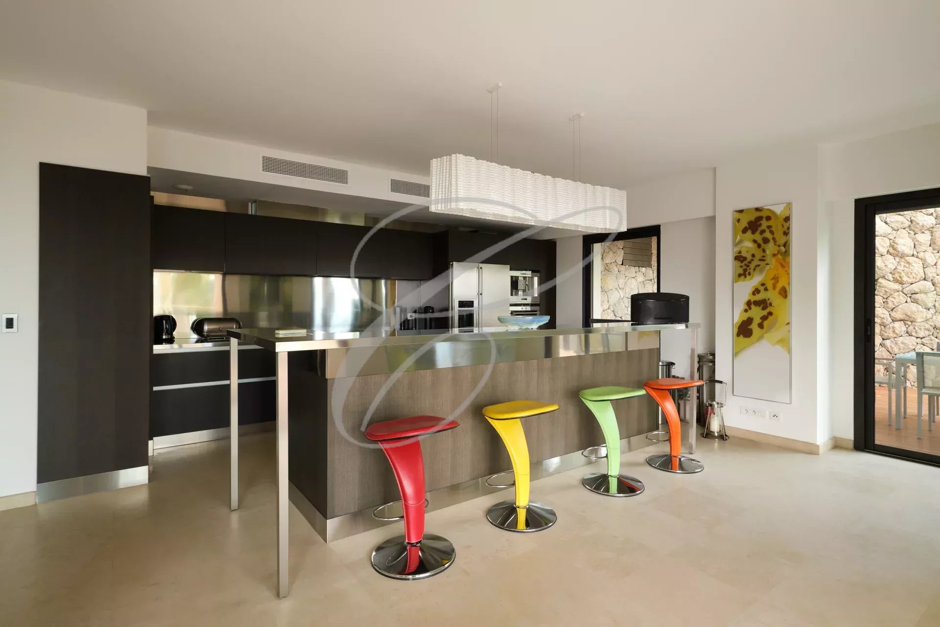 Cuisine moderne avec bar et chaises colorées dans une villa contemporaine à Roquebrune-Cap-Martin.