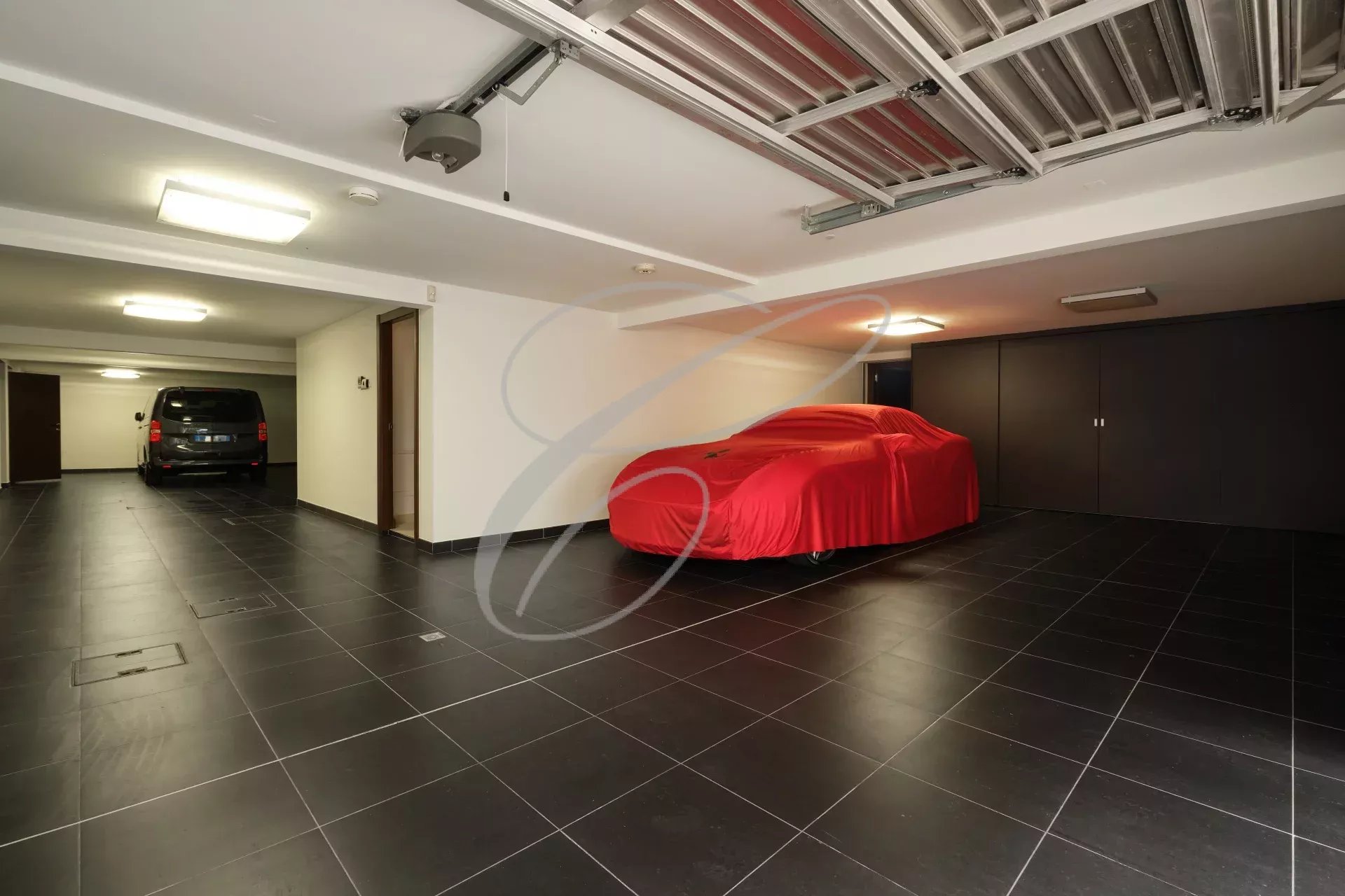Garage d'une villa contemporaine à Roquebrune-Cap-Martin avec voiture recouverte et espace de stationnement.