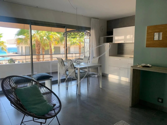 Intérieur d'un appartement moderne avec vue sur la mer, mobilier contemporain et grandes fenêtres.