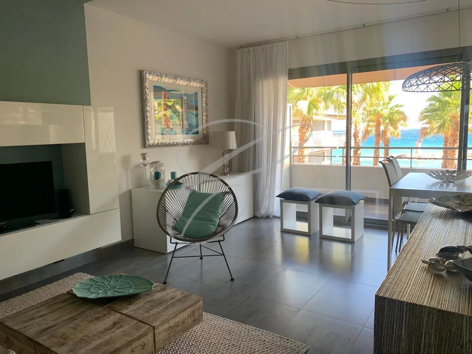 Intérieur d'un appartement moderne avec vue sur la mer, mobilier contemporain et balcon.