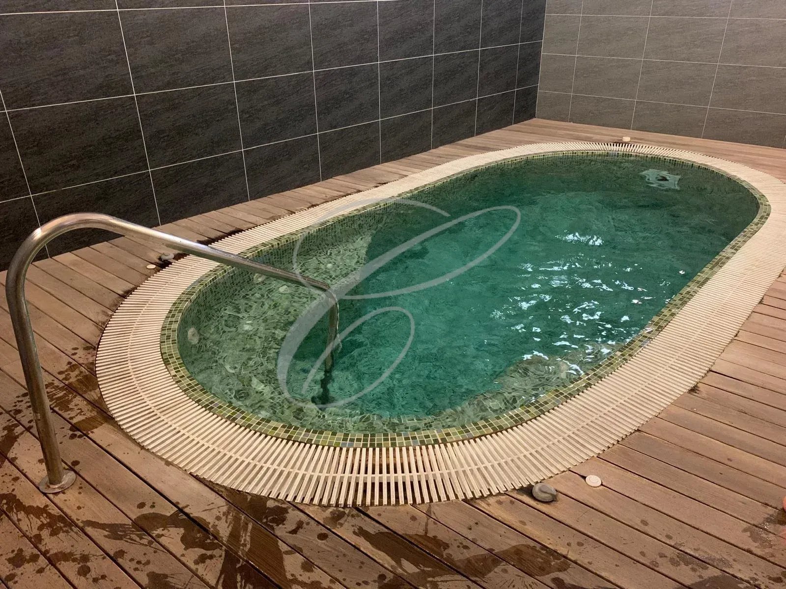 Petite piscine intérieure avec eau claire et margelle en bois