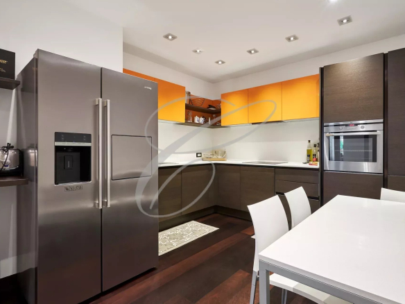 Cuisine moderne avec meubles orange et marron, table à manger et électroménagers en acier inoxydable.