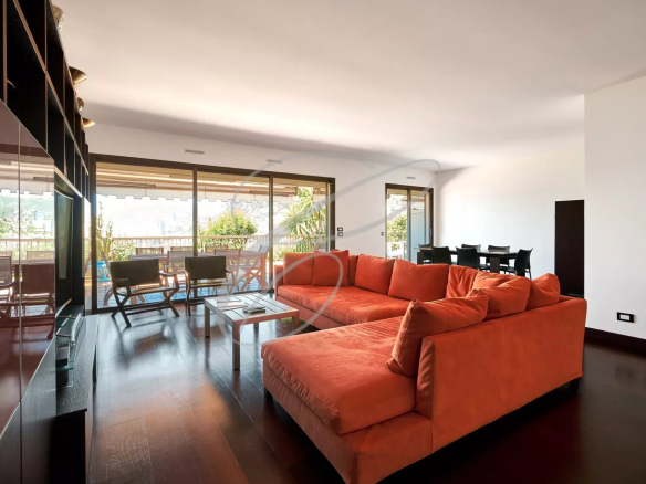 Intérieur d'un appartement spacieux avec un salon orange et une vue sur la mer.