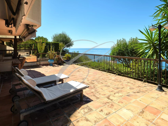 Terrasse avec vue sur la mer et Monaco, chaises longues sur le sol en carrelage.