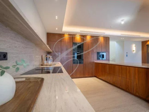 Cuisine moderne avec des meubles en bois et un plan de travail en marbre dans une villa à Nice.