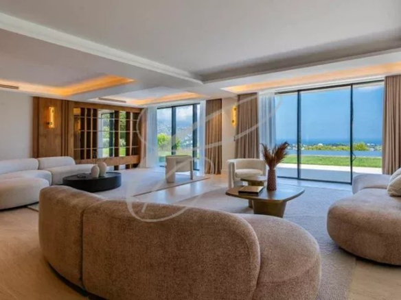Intérieur d'une villa luxueuse avec un salon spacieux et lumineux, vue sur la mer.