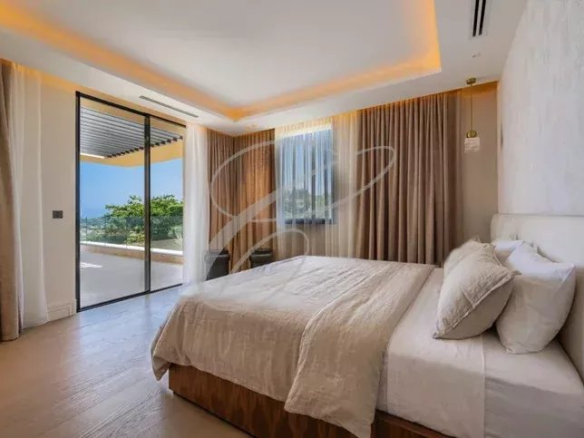 Chambre lumineuse avec lit double et accès à une terrasse, vue sur la nature.