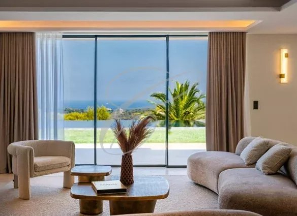 Intérieur d'une villa luxueuse à Nice avec vue sur la mer et montagnes, salon moderne et lumineux.