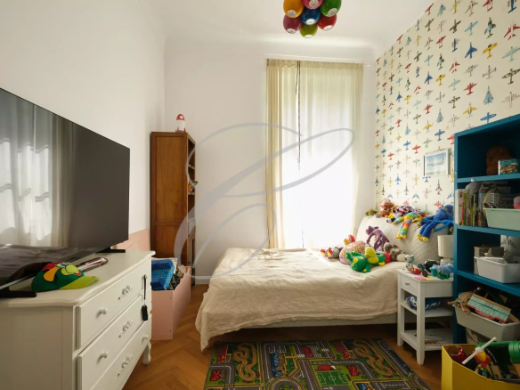 Chambre d'enfant avec lit, télévision et étagères remplies de jouets.