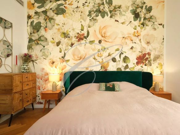 Chambre avec lit double et mur décoré de fleurs, éclairage doux.