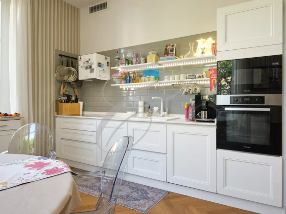 Cuisine moderne avec des meubles blancs et des étagères, éclairage LED, et table à manger.