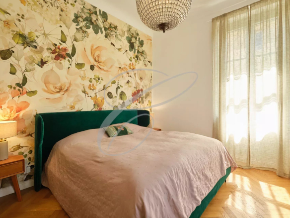 Chambre avec un lit double, décoration florale et lumière naturelle à Roquebrune-Cap-Martin.