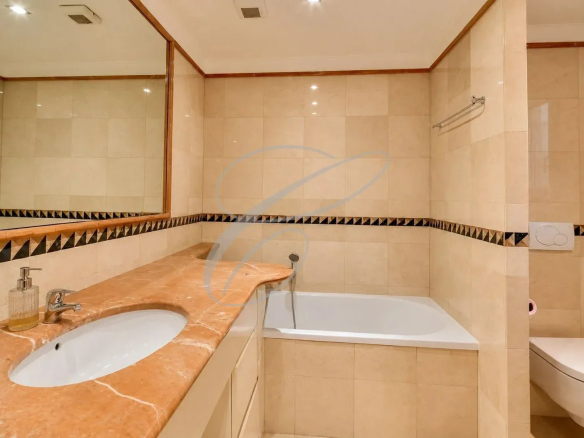 Salle de bain avec baignoire, lavabo et miroir dans un appartement de luxe.
