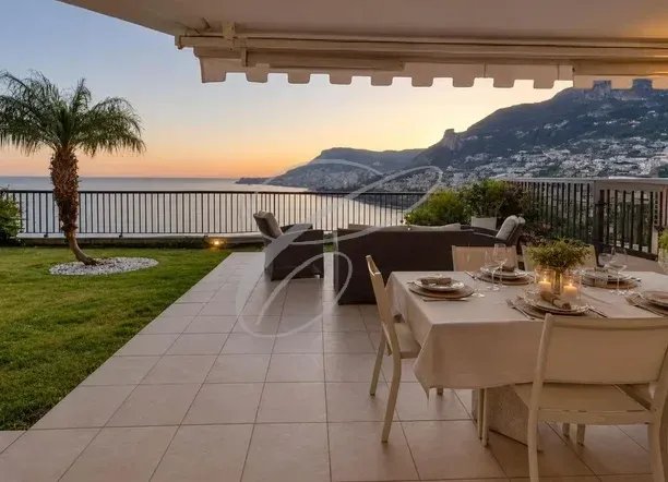 Terrasse avec vue sur la mer à Roquebrune-Cap-Martin Terrasse d'un appartement avec vue sur la mer et les montagnes, mobilier de jardin et table dressée.