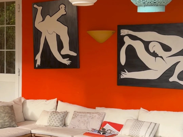 Intérieur d'une villa avec murs orange, canapés blancs et œuvres d'art modernes.