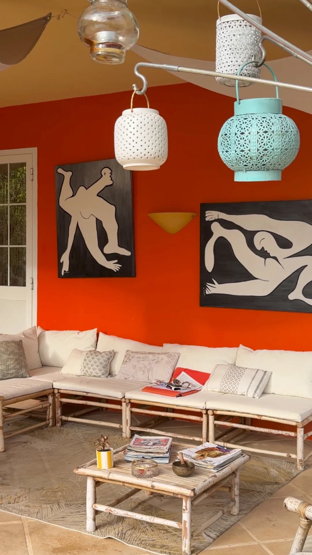 Intérieur d'une villa avec murs orange, canapés blancs et œuvres d'art modernes.