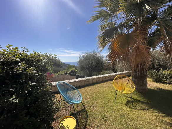 Jardin d'une villa avec chaises colorées et vue sur la mer, à Sainte-Agnès.