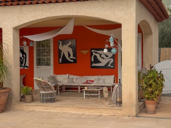 Terrasse d'une villa avec salon extérieur et piscine, entourée de verdure.