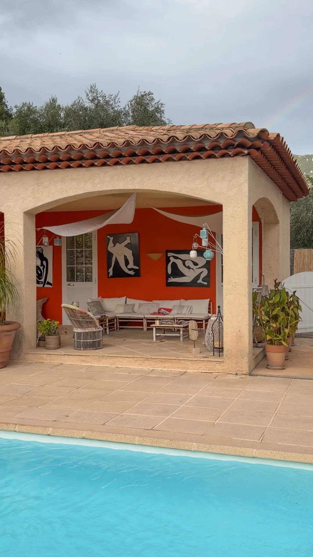 Terrasse d'une villa avec salon extérieur et piscine, entourée de verdure.