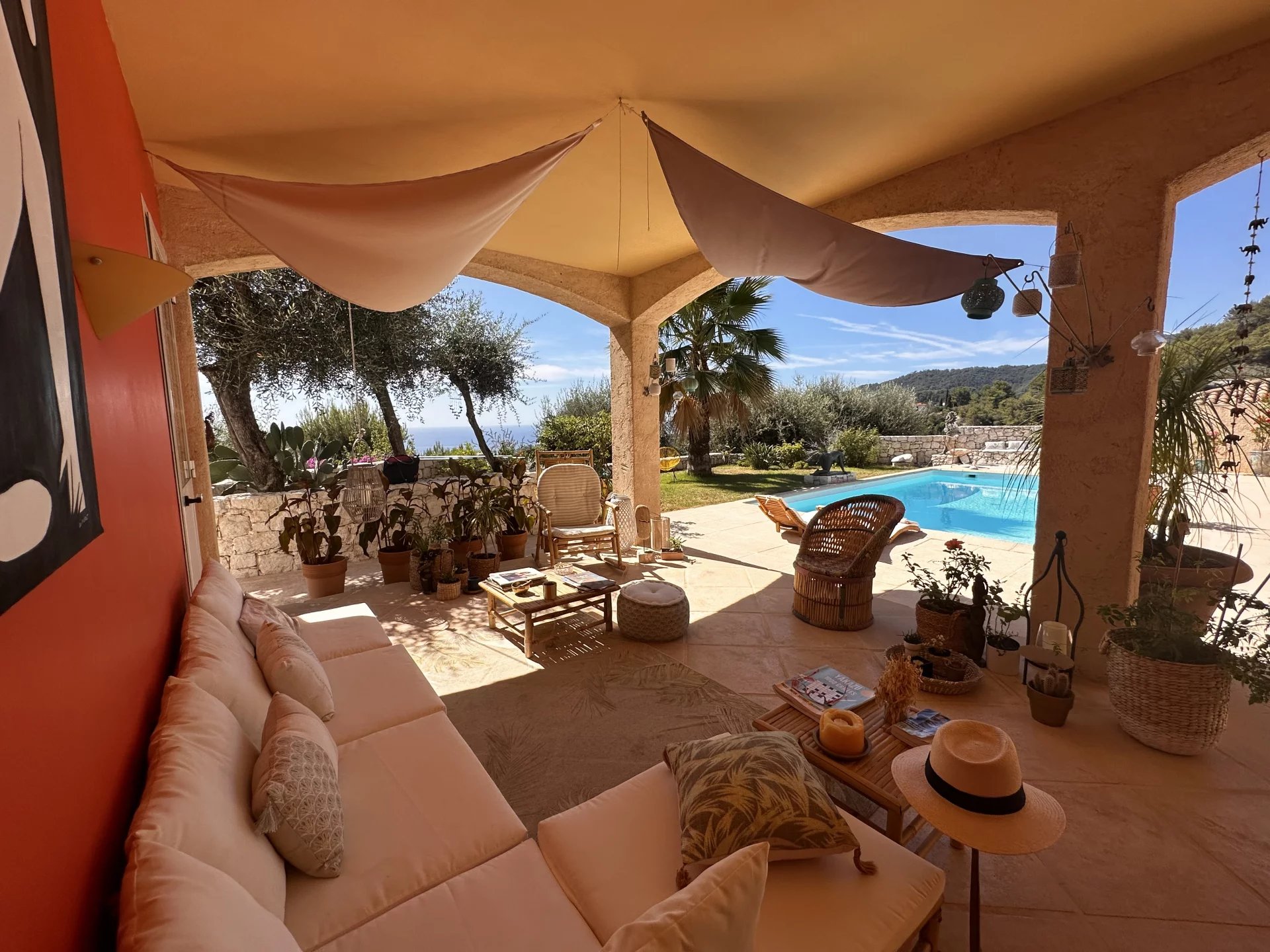 Terrasse d'une villa avec salon extérieur, piscine et vue sur la mer et les montagnes.