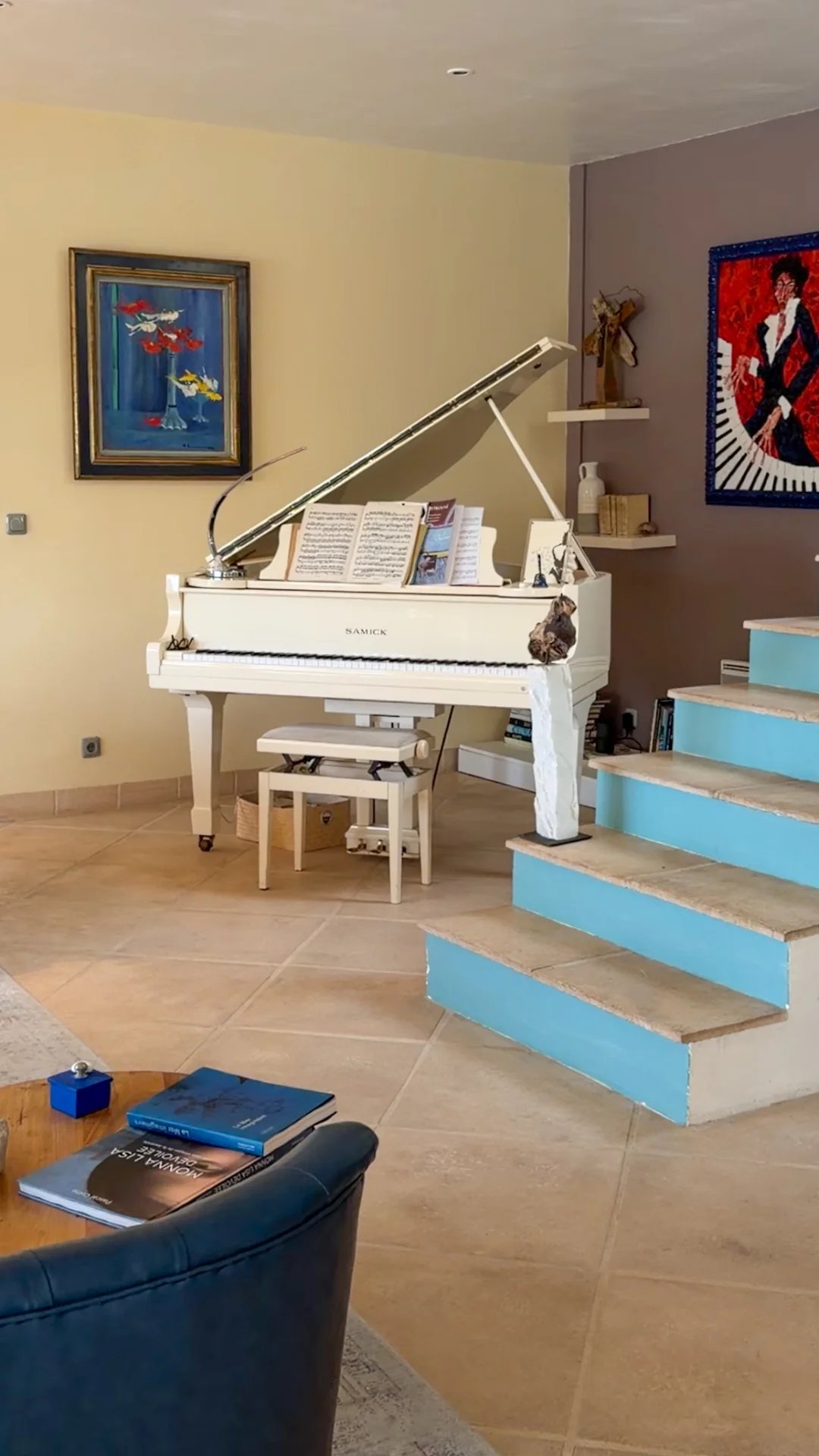 Intérieur d'une villa avec un piano blanc, un salon spacieux et des escaliers menant à un étage supérieur.