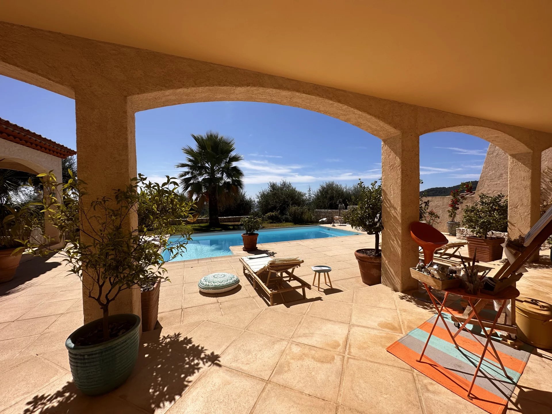 Vue depuis une terrasse d'une villa avec piscine, jardin et palmier, ciel bleu à Sainte-Agnès.