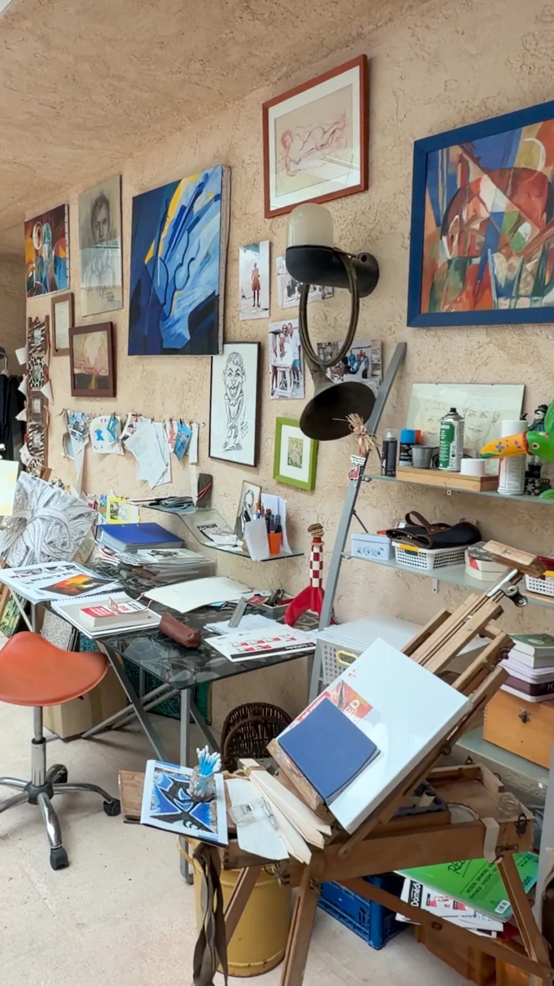 Atelier d'art avec tables, fournitures et œuvres accrochées au mur.