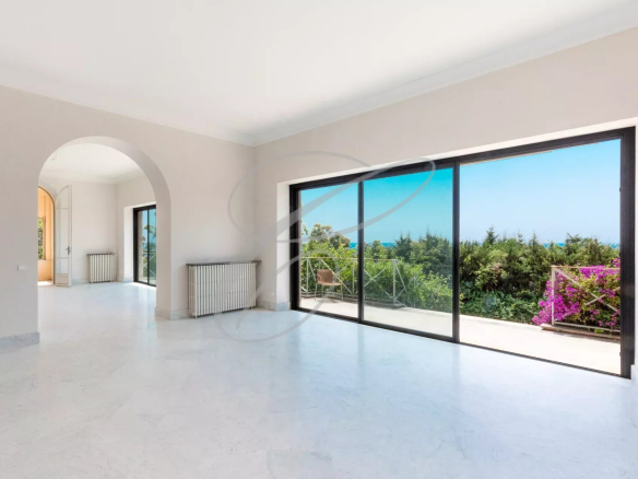 Interior of a villa with large windows overlooking a flower garden in Menton.