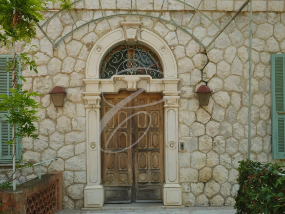 Entrance to a 19th century villa with a wooden door, stone walls and green shutters.