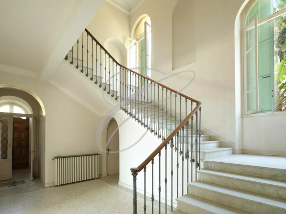 Interior of a villa with an elegant staircase and bright windows.