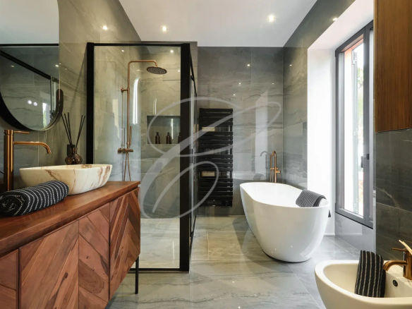 Salle de bain moderne avec baignoire, douche et meuble en bois.