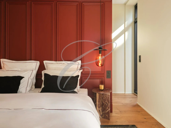 Chambre d'une propriété rénovée avec un mur rouge et un éclairage suspendu.