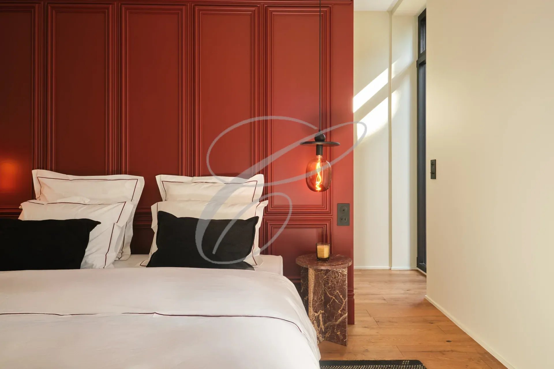Chambre d'une propriété rénovée avec un mur rouge et un éclairage suspendu.